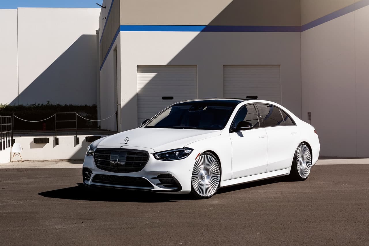 Premium white Mercedes-Benz sedan featuring custom Lexani wheels, parked outdoors in front of a modern building.